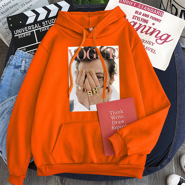 Large orange hoodie with a Vogue magazine print, featuring long bat sleeves and a hooded collar, styled as streetwear.
