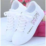 Girls' white leather sneakers with cat design and rubber sole.